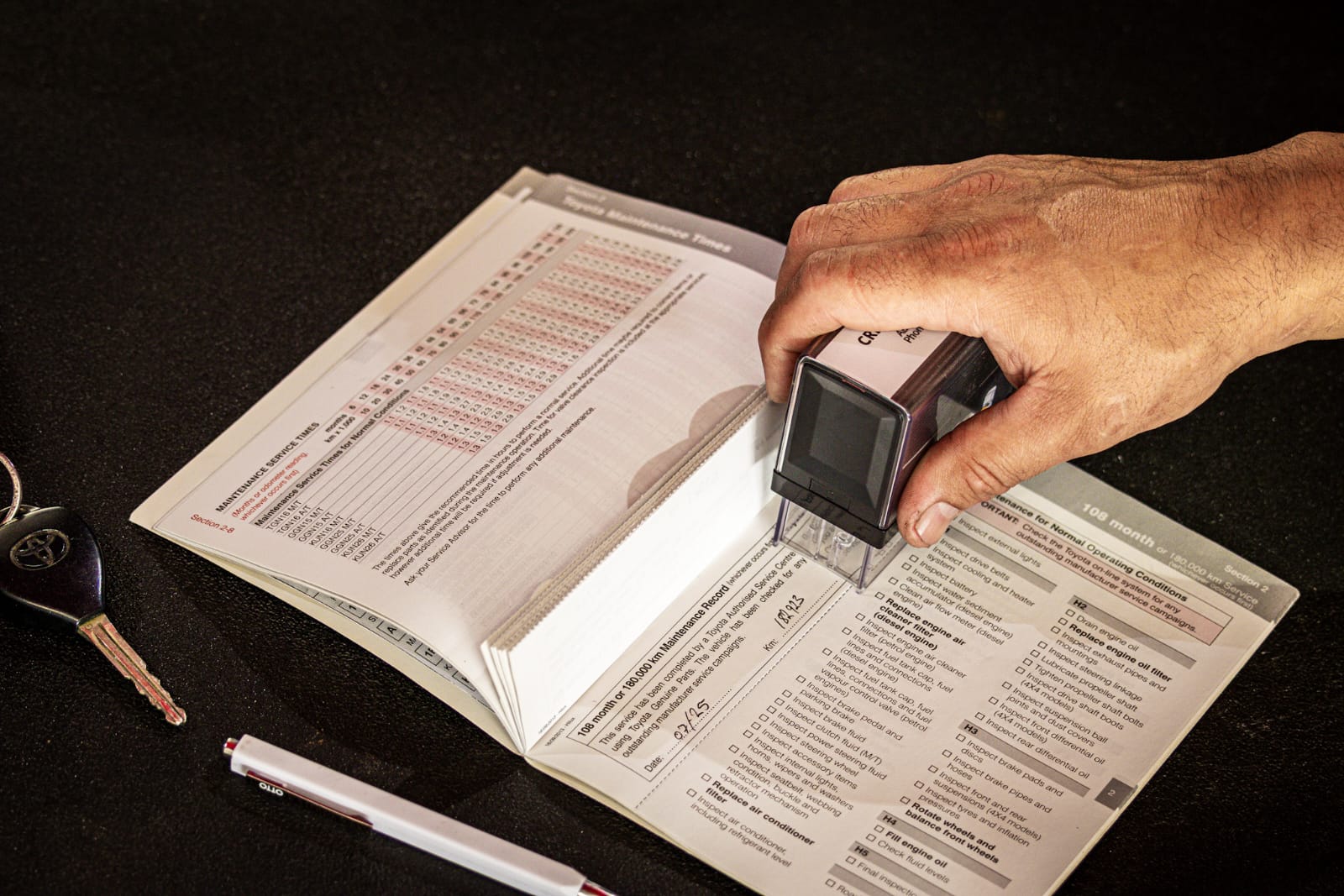 Cole stamping a vehicle logbook after a service